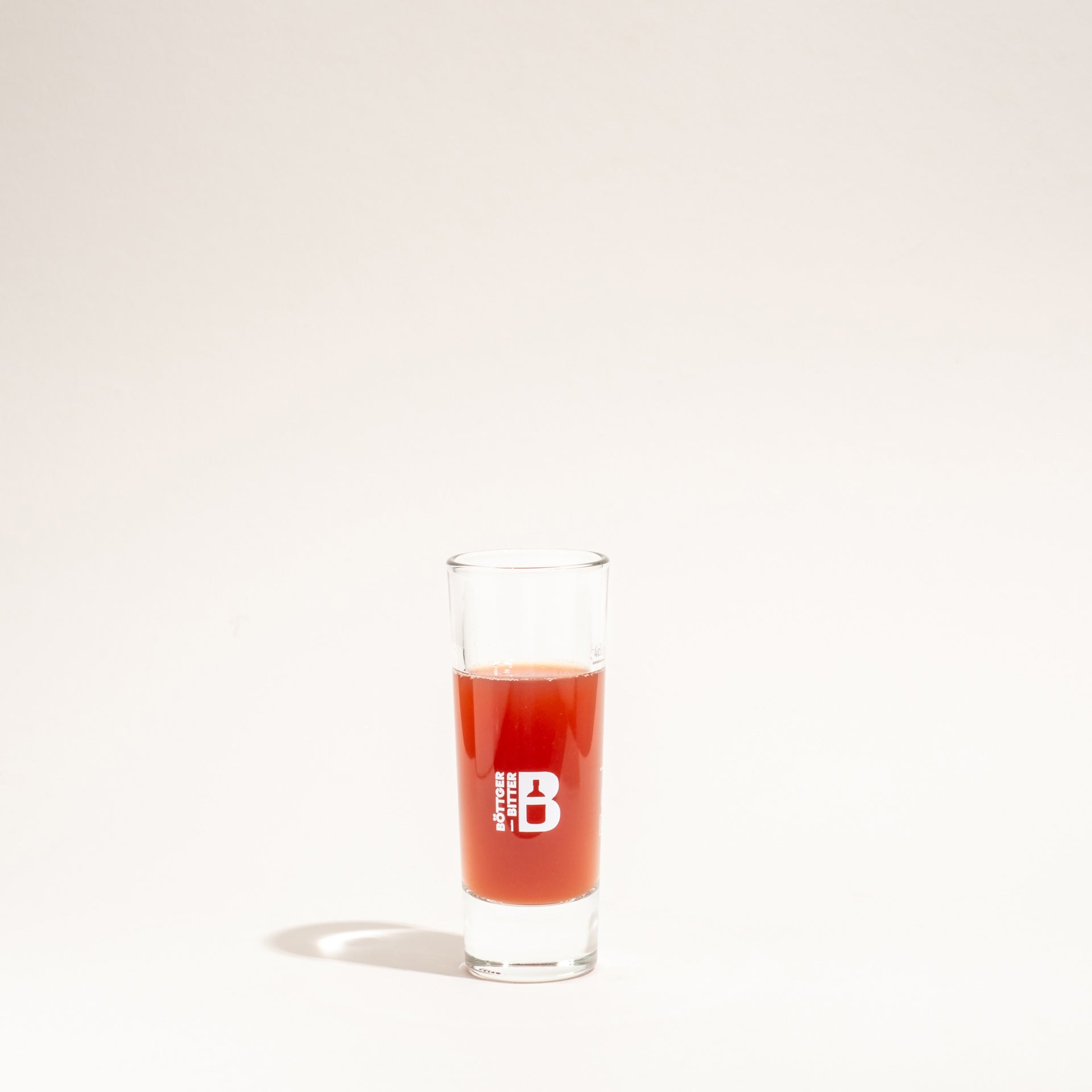 Ein schmales Böttger-Shotglas mit Logo-Aufdruck, gefüllt mit einem roten Likör.